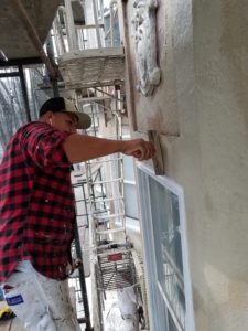 House painter demonstrating how to patch peeling stucco