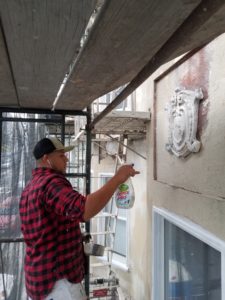 House painter demonstrating how to patch peeling stucco