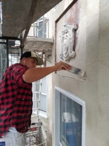 House painter demonstrating how to patch peeling stucco